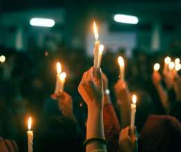 People taking part in a vigil holding up lit candles