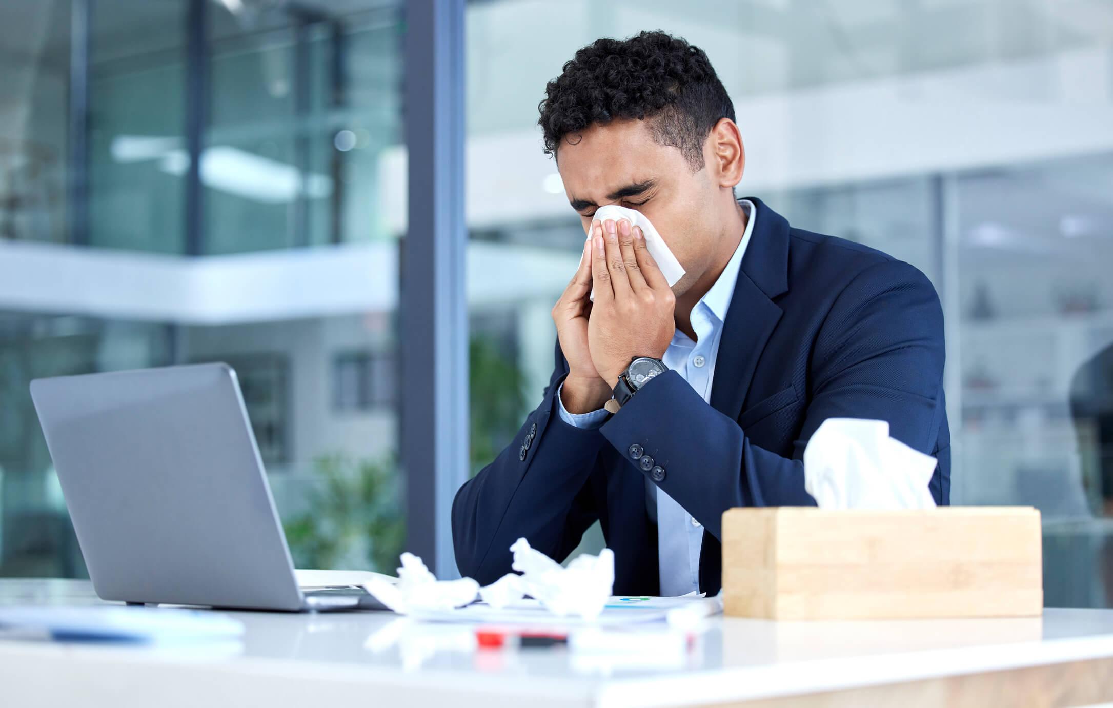 Sick man blowing his nose at work